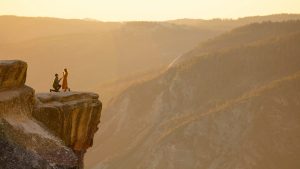 Dos personas en un acantilado bajo un precioso atardecer