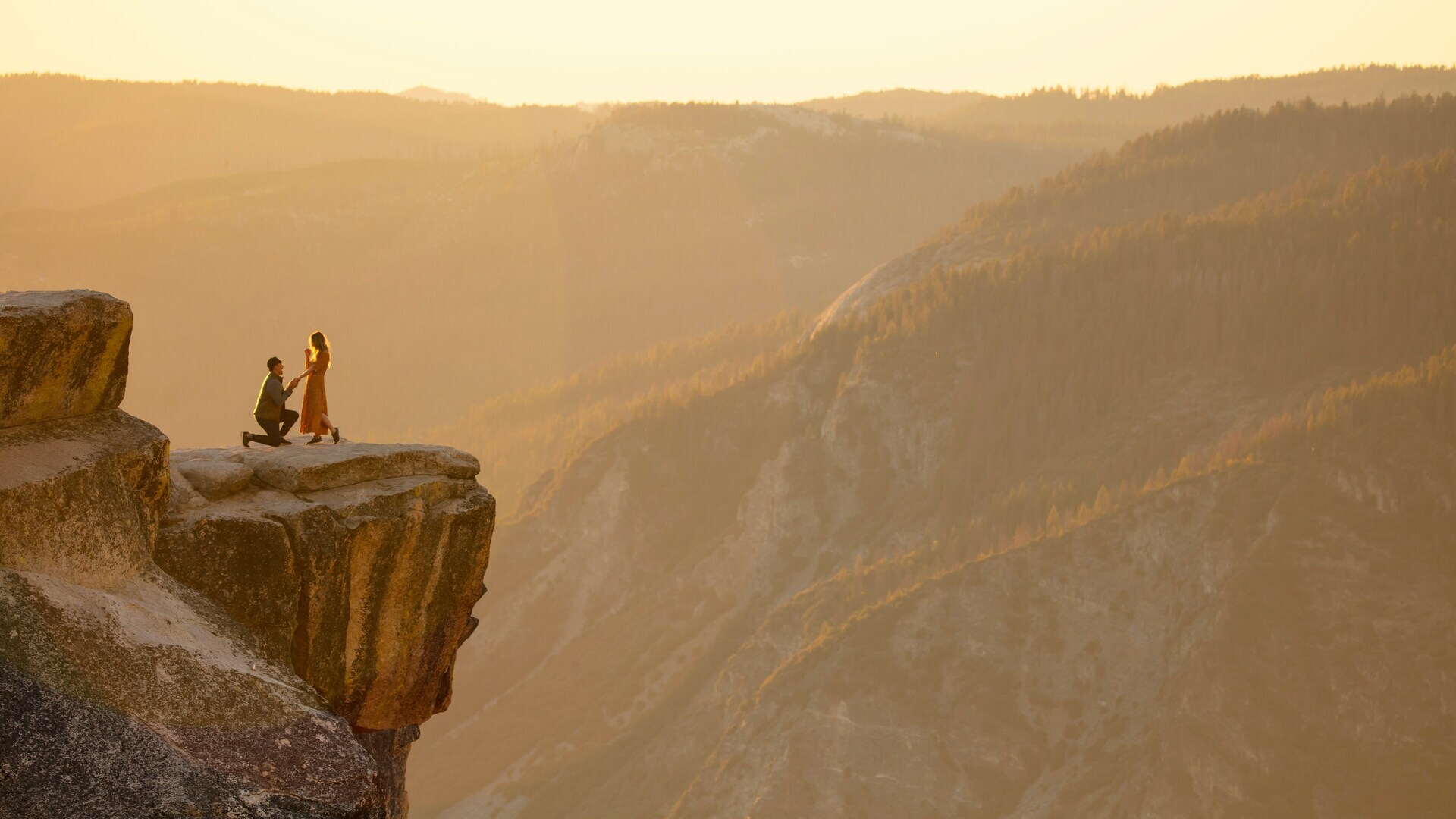 Dos personas en un acantilado bajo un precioso atardecer