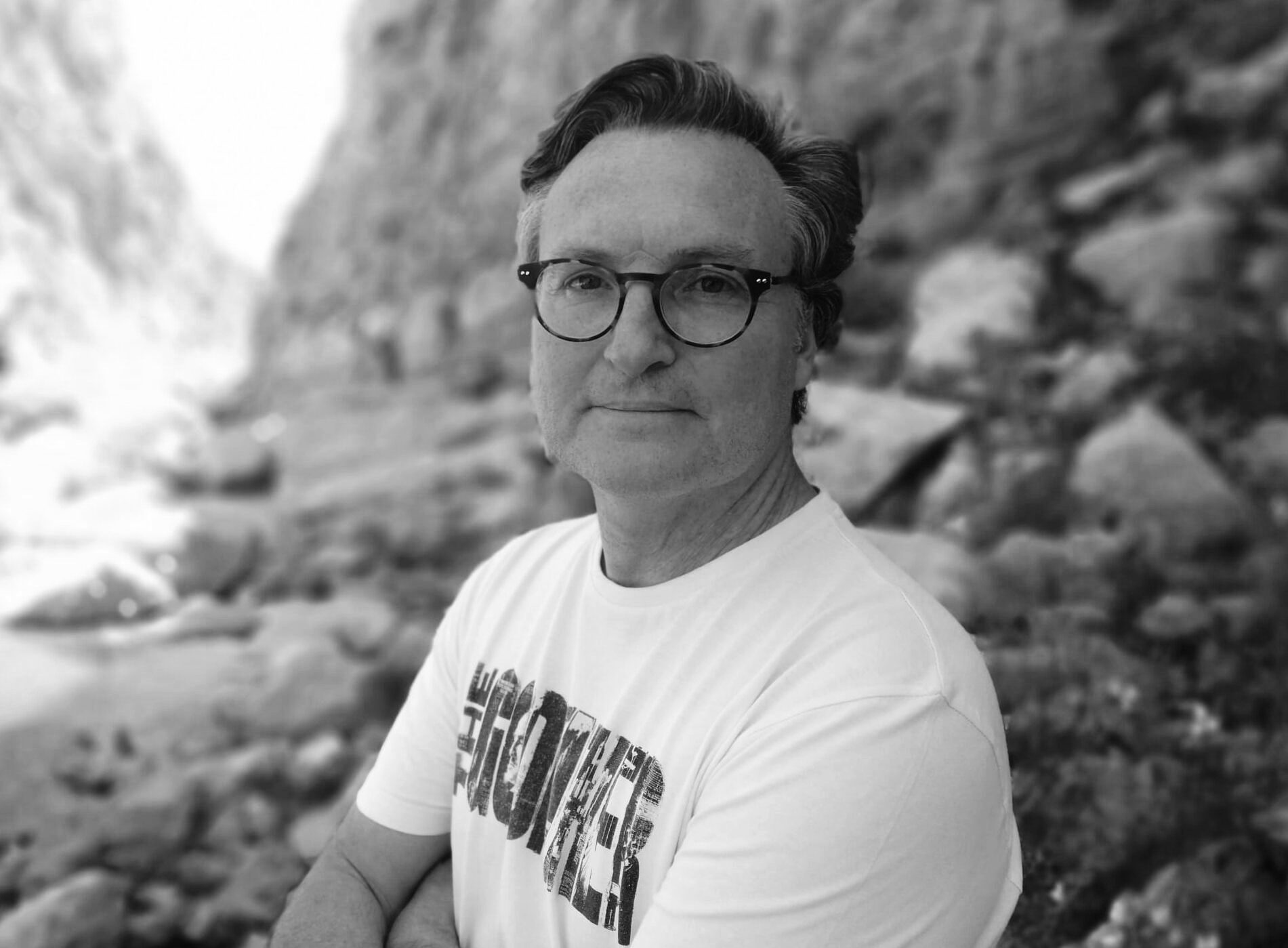 Hombre mediana edad con gafas. Al fondo una playa. 